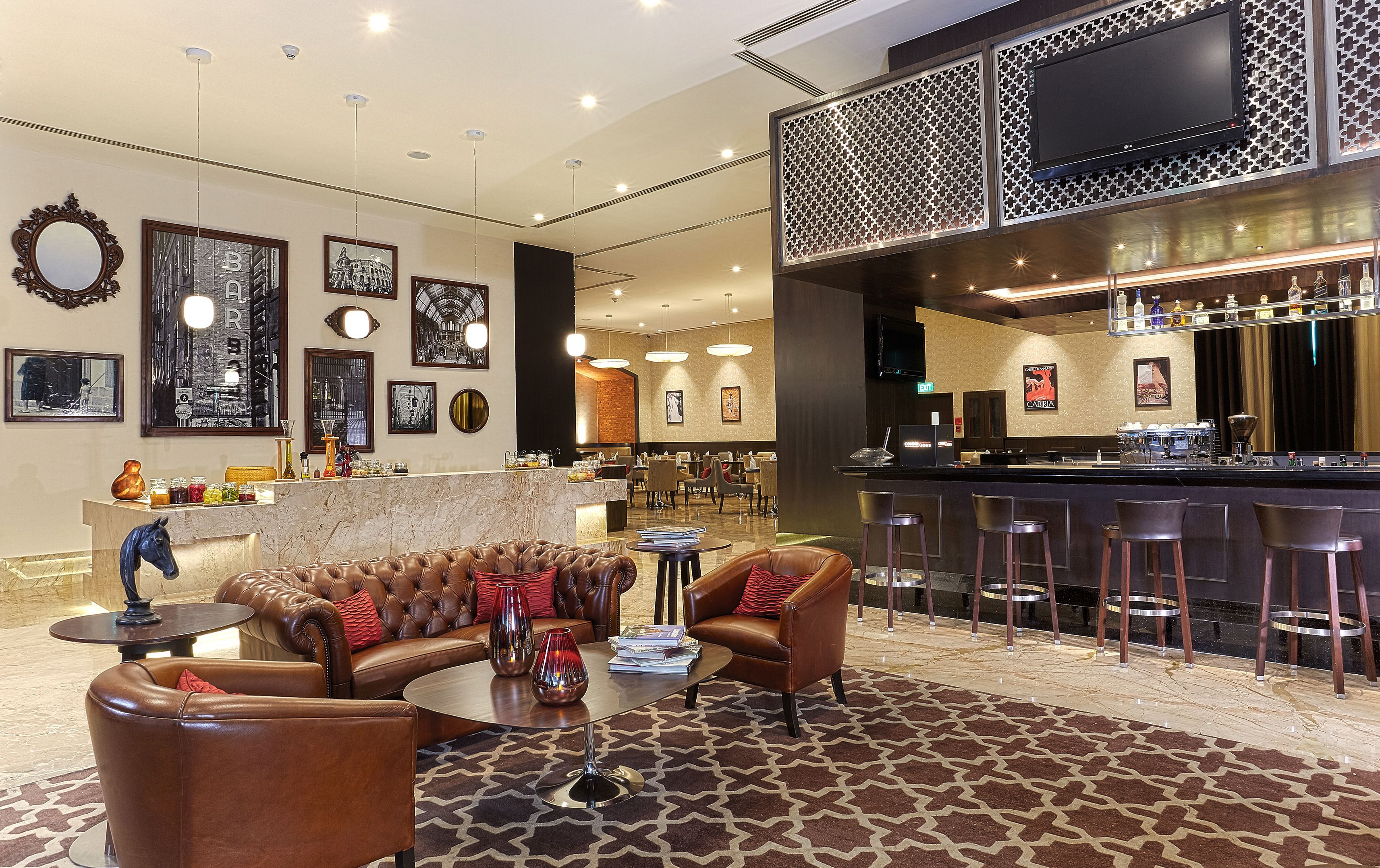 A hotel lobby with a bar area, leather seating, and artwork on the walls.