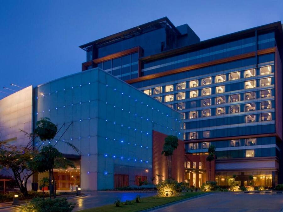 A modern hotel with a glass facade, multiple floors, and a well-lit entrance.
