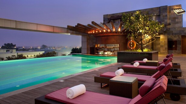Zona de piscina exterior con sillones de descanso y un bar.