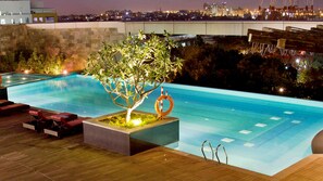Piscina exterior con cubierta de madera, sillas de descanso, jardinera y boya salvavidas.