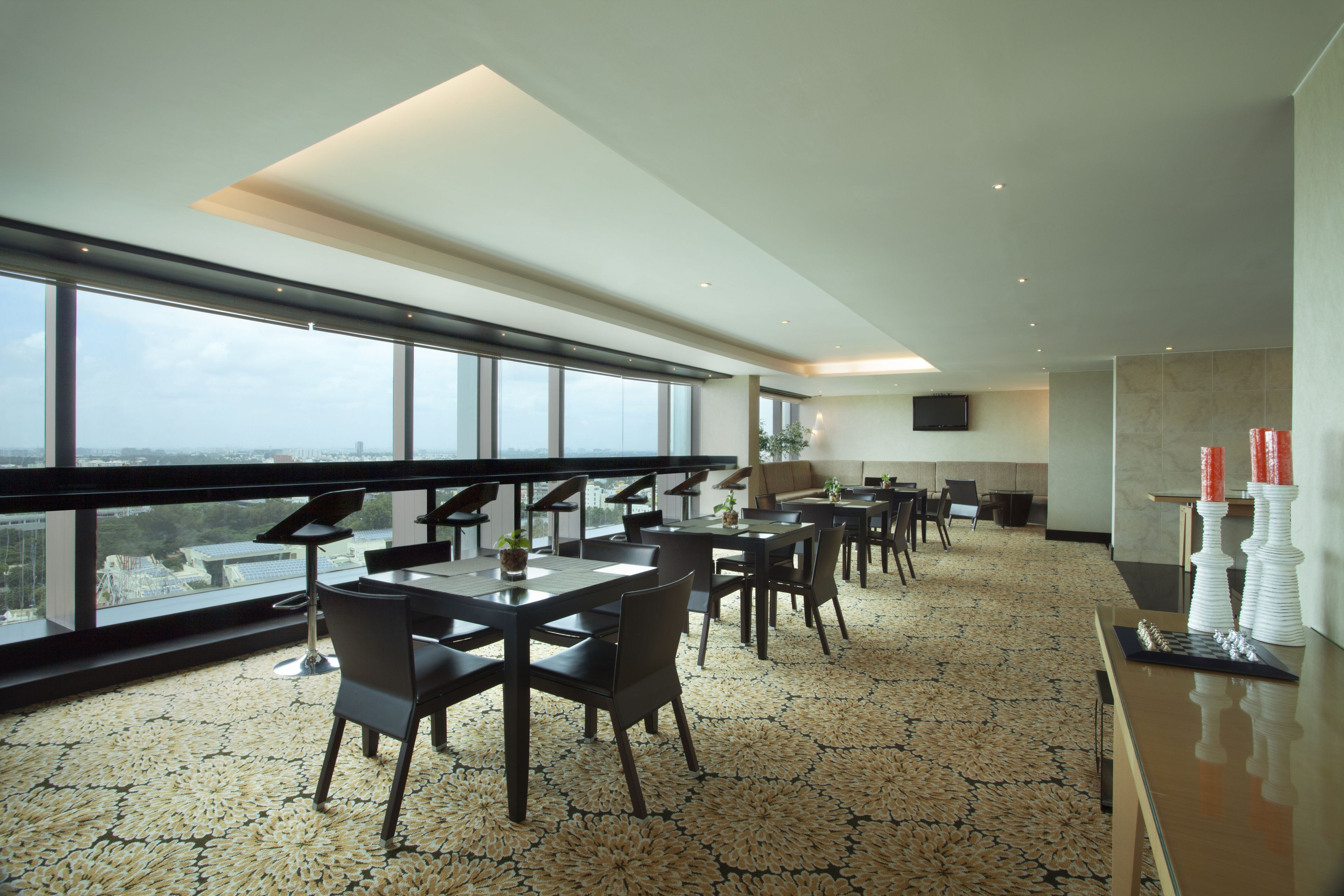 A modern dining area with large windows, a piano, and a chessboard.