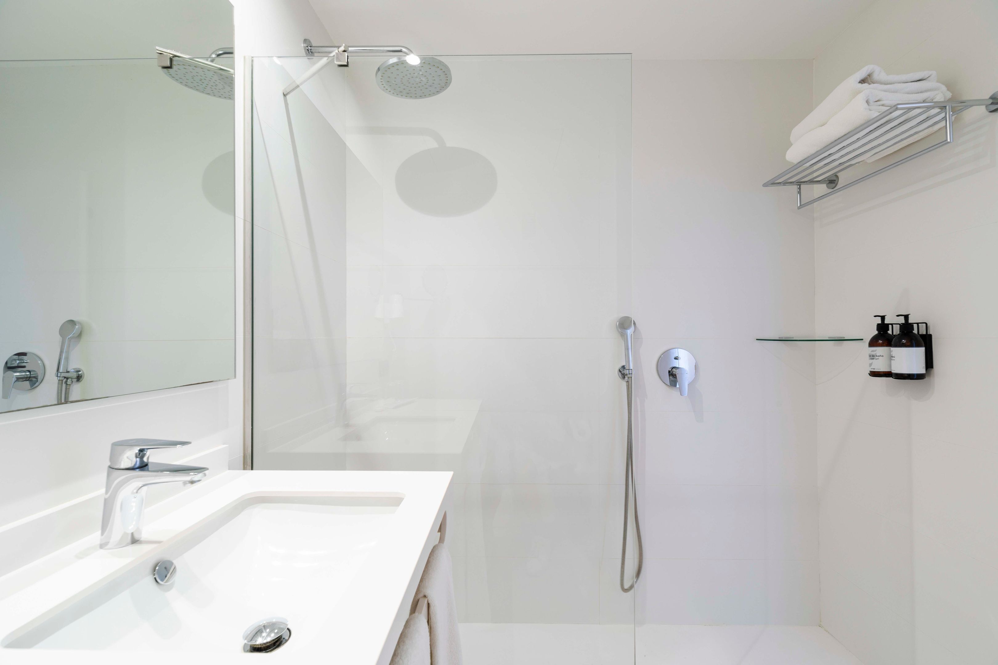 A modern bathroom with a glass-enclosed shower, a white sink, and a towel rack.