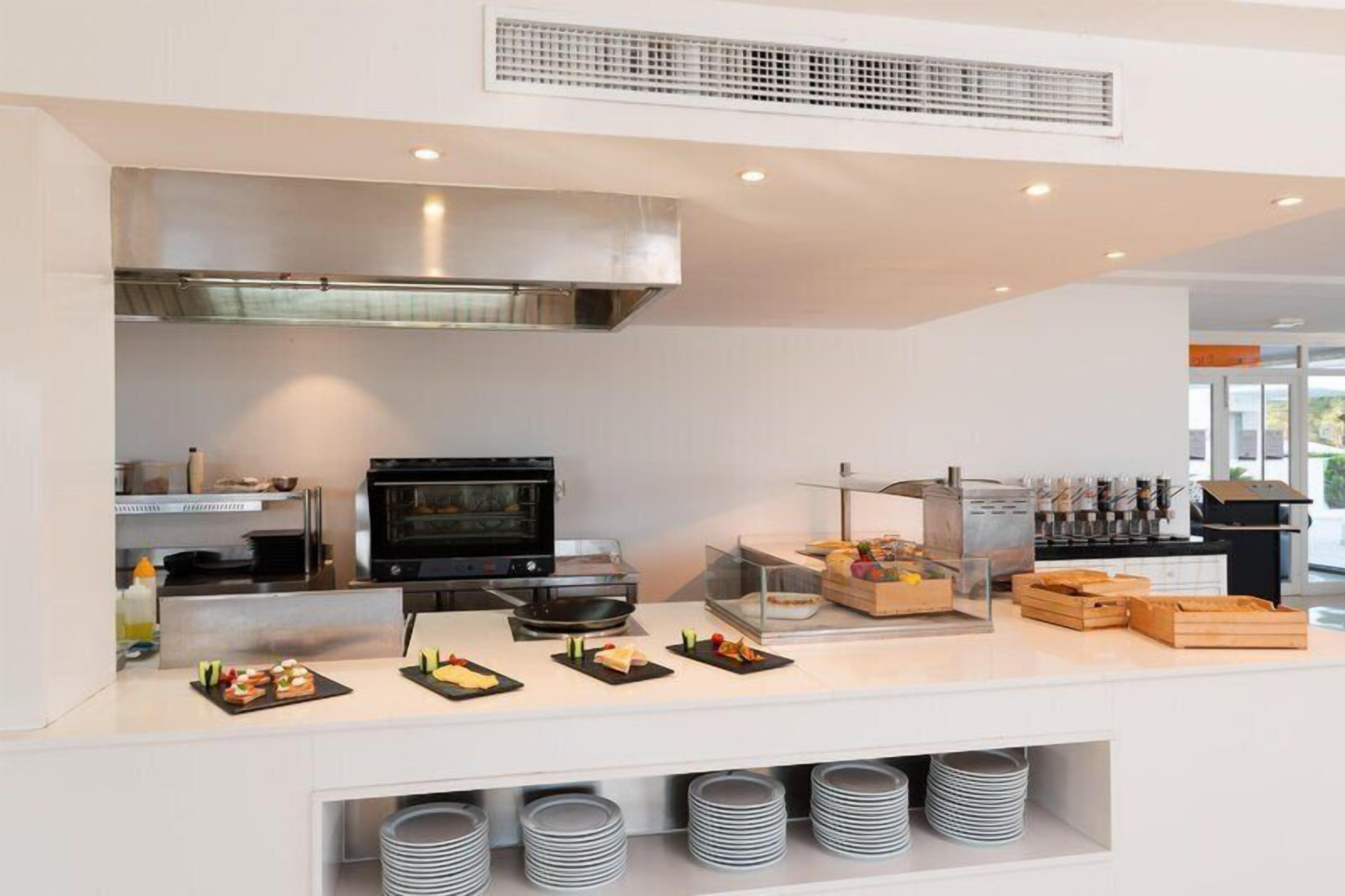 A modern kitchen with a built-in oven, a microwave, and a buffet area with various food items and utensils.