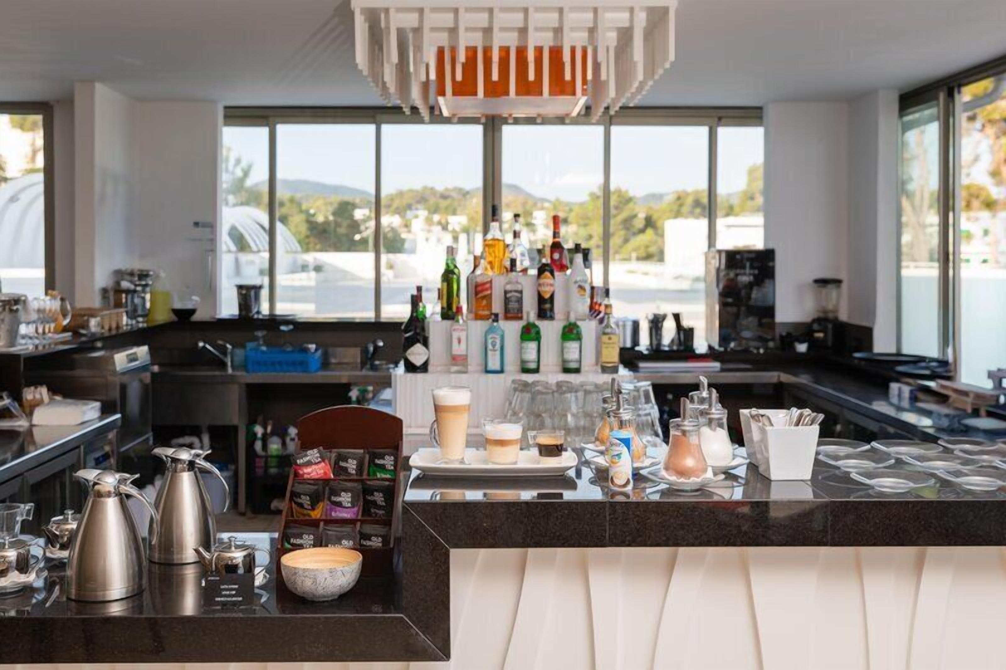A modern bar area with a variety of bottles, glasses, and a coffee machine.