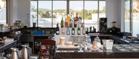 A modern bar area with a variety of bottles, glasses, and a coffee machine.