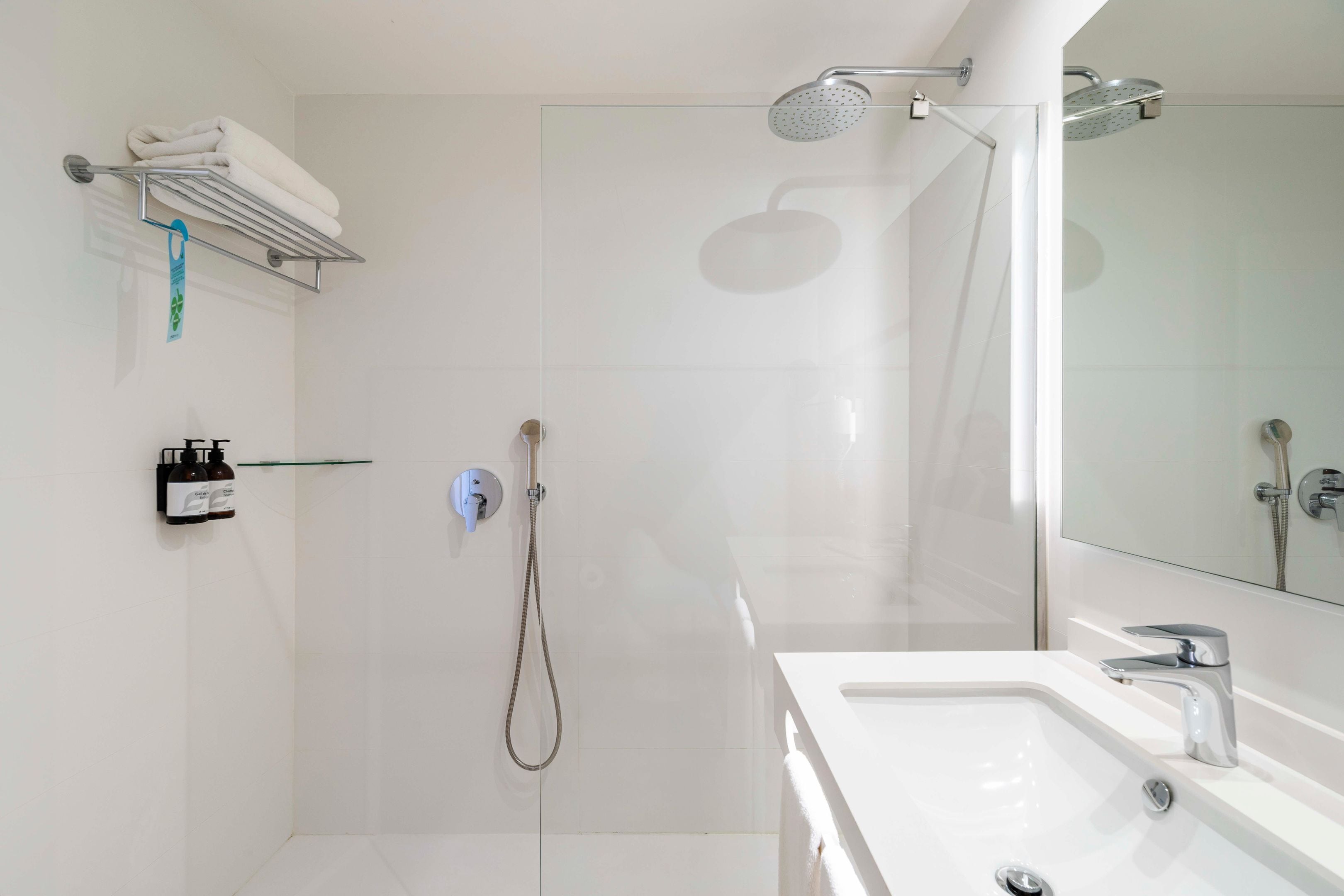 A modern bathroom with a glass shower enclosure, a white sink, and a towel rack.