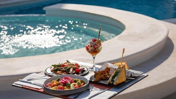 A poolside dining setup with a salad, sandwich, and cocktail. - Hotel THB Naeco Ibiza - Adults Only (Sant Josep de sa Talaia)