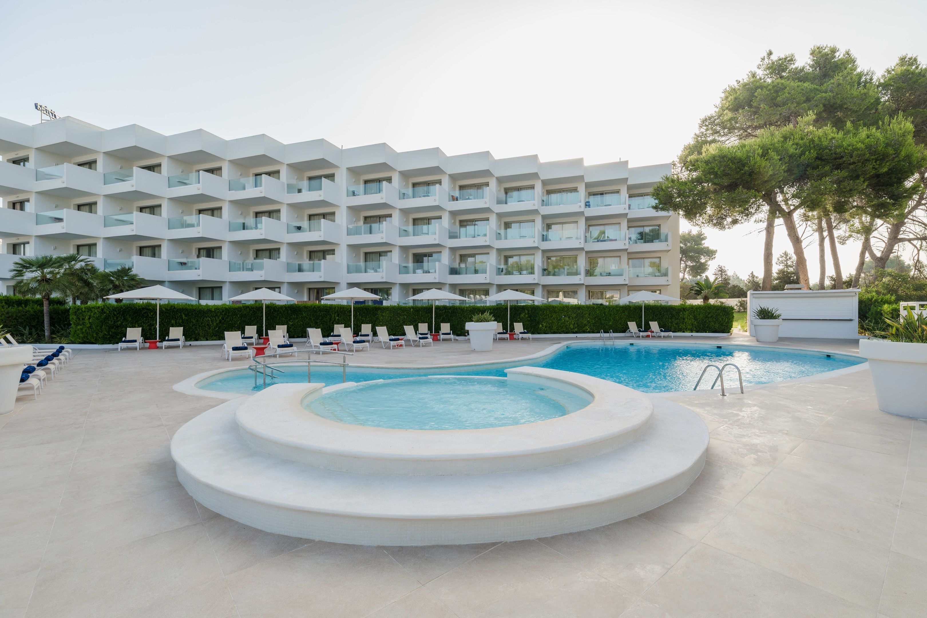 A modern hotel with a pool area, including a hot tub and lounge chairs.