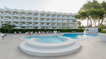 A modern hotel with a pool area, including a hot tub and lounge chairs.