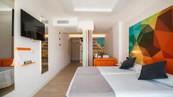Een moderne hotelkamer met een groot bed, een aan de muur bevestigde televisie en een kleurrijk geometrisch kunstwerk.