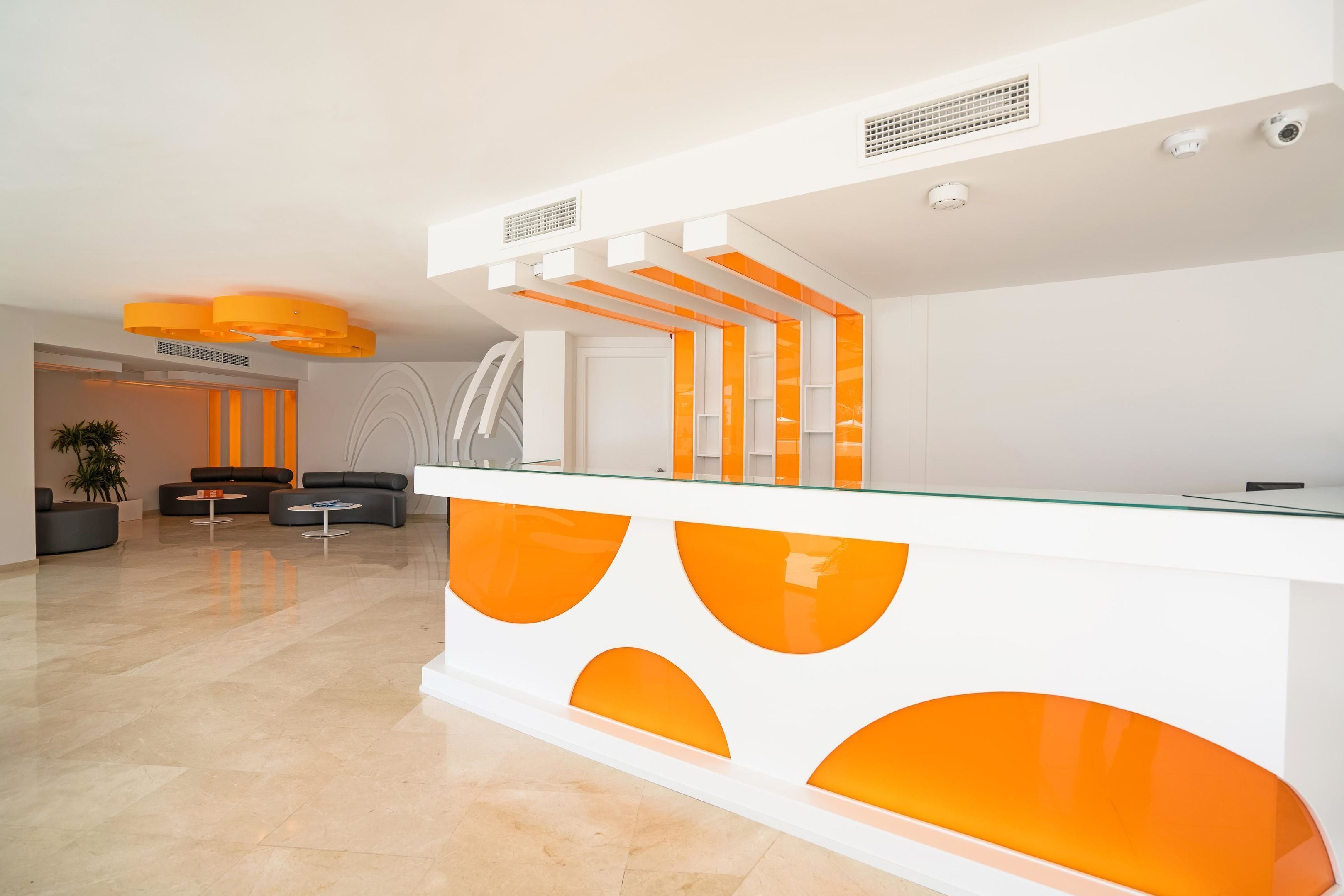 A modern reception area with a glass counter, seating area, and a staircase.