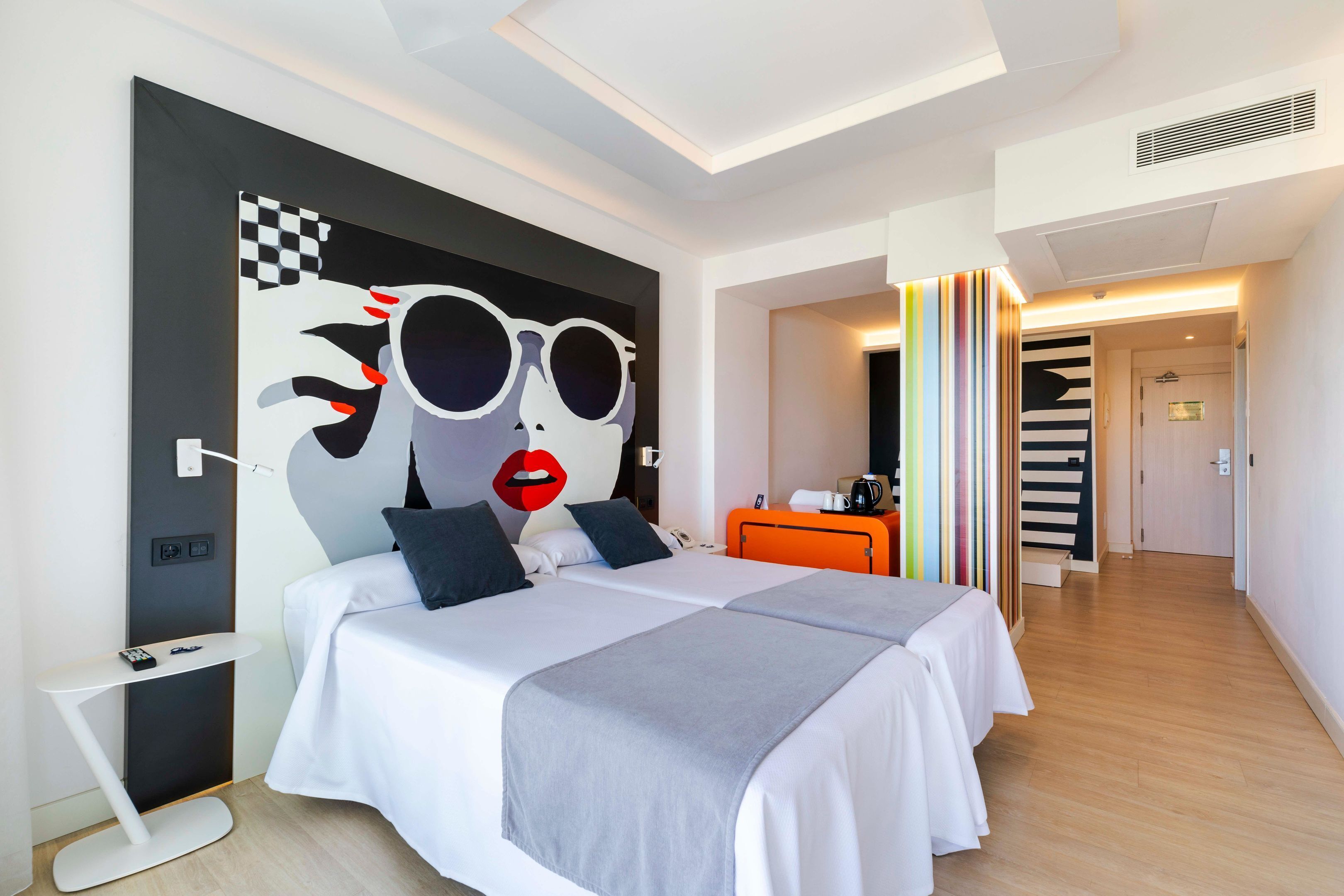 Una habitación de hotel moderna con una cama grande, una mesita de noche y un diseño gráfico en la pared.