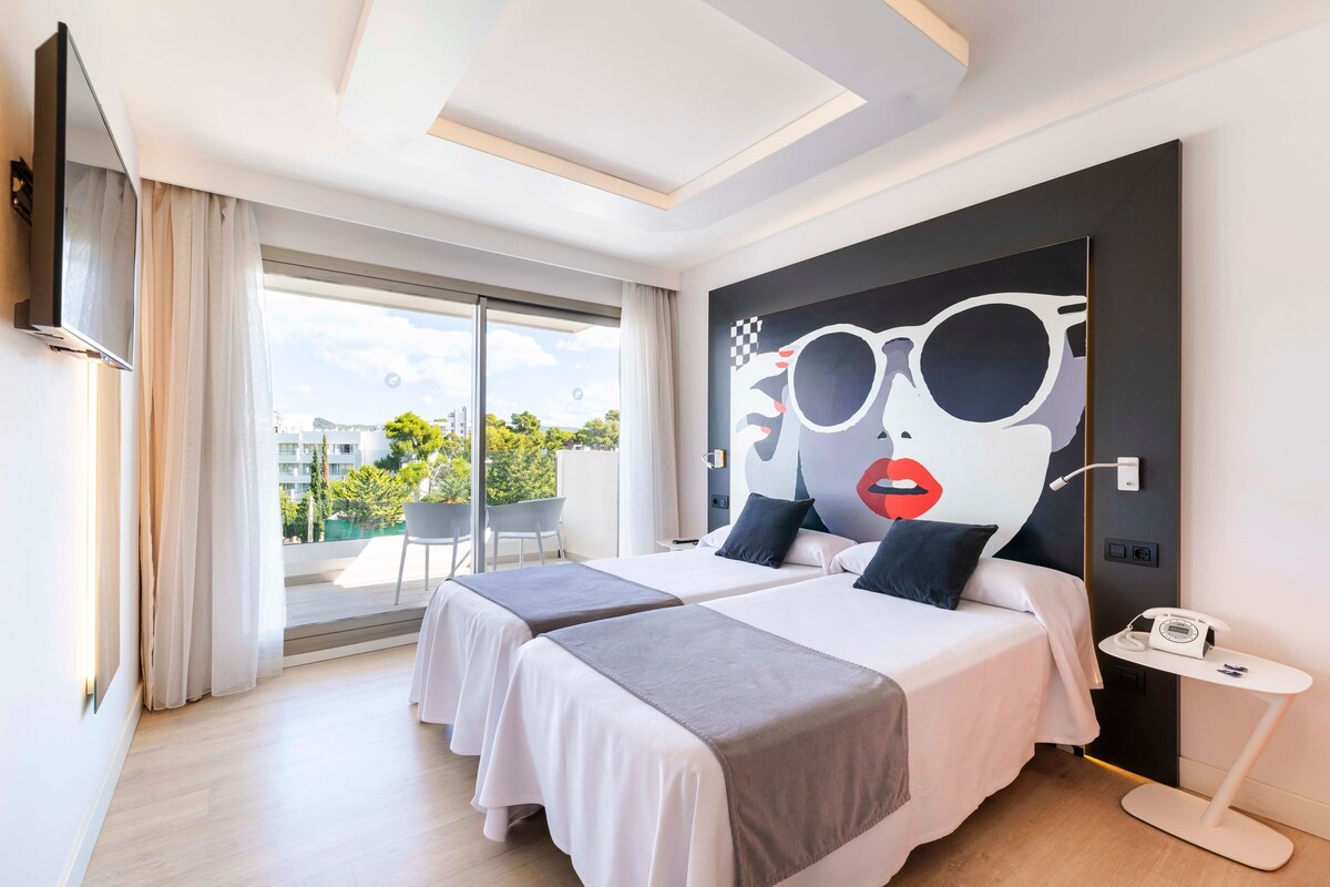 A modern hotel room with two beds, a large window with a view, a mounted TV, and a small table with a phone.