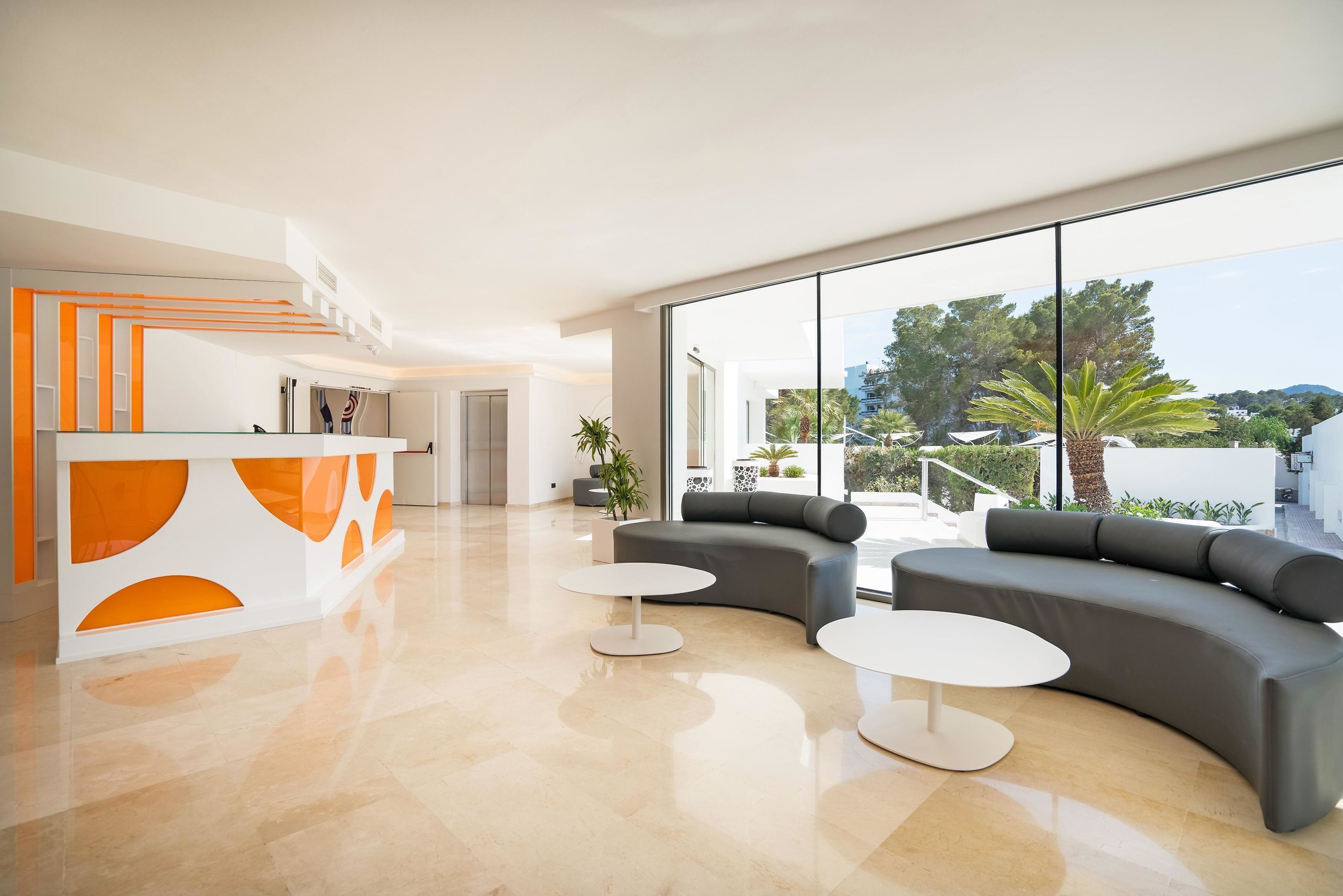 A modern lobby with a reception desk, two sofas, and a large window offering a view of the outdoors.