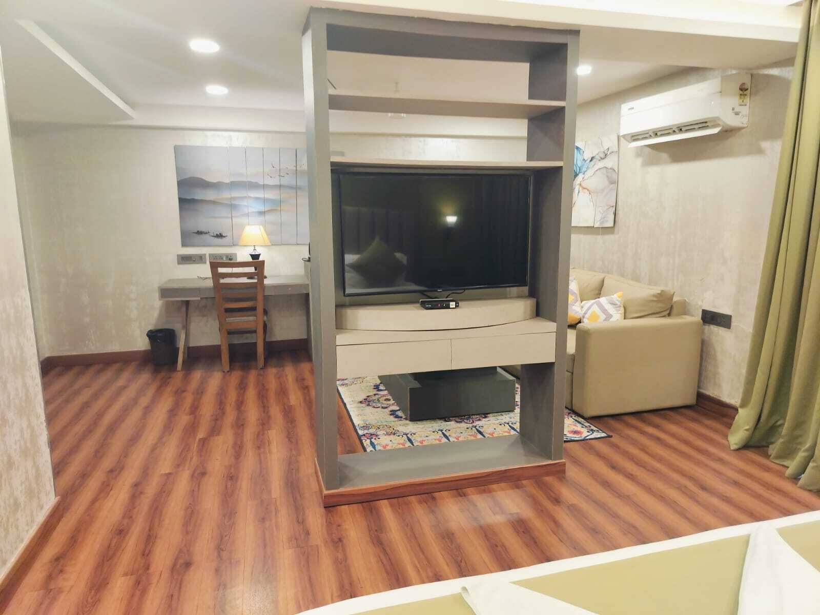 A living room with a TV, a sofa, a desk, and a chair.