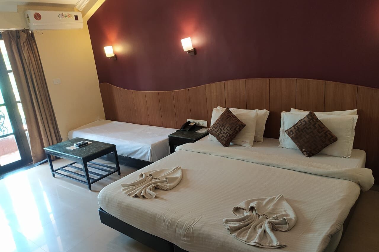 A hotel room with two beds, a small table, and a nightstand.