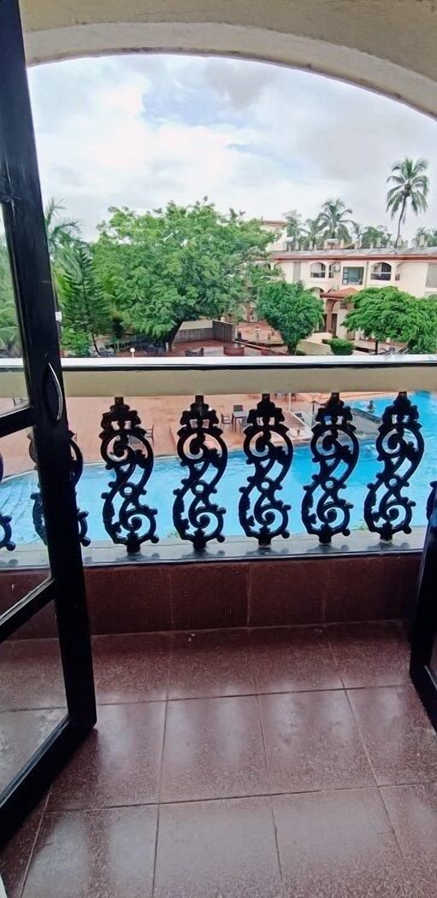 Uitzicht vanaf een balkon met een zwembad, met betegelde vloer en een sierhekwerk.