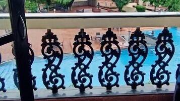 Uitzicht vanaf een balkon met een zwembad, met betegelde vloer en een sierhekwerk.