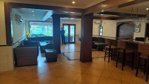 Um saguão com balcão de recepção, área de estar e vista para o exterior.