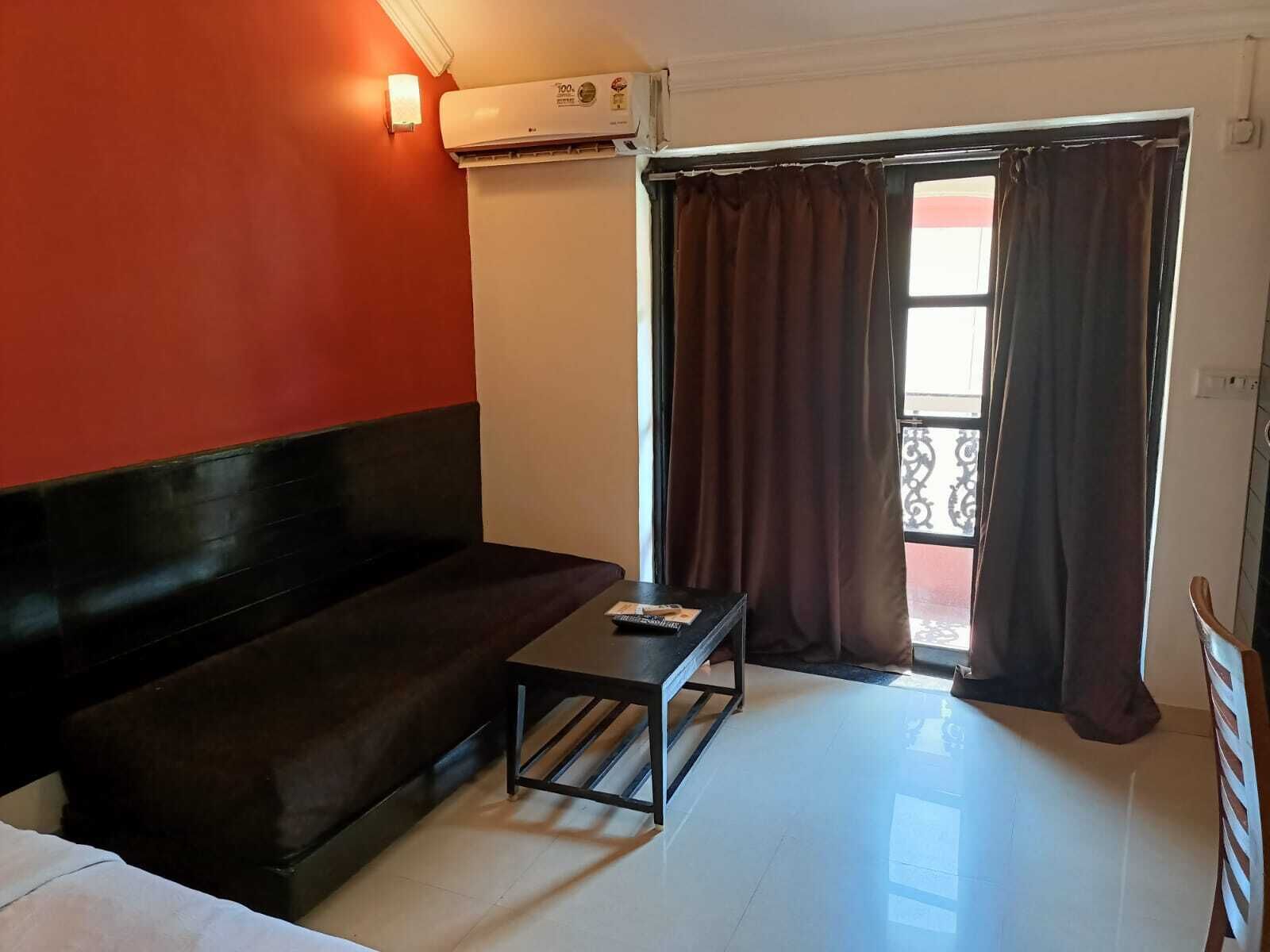 A room with a dark-colored sofa, a small table, and a window with curtains.