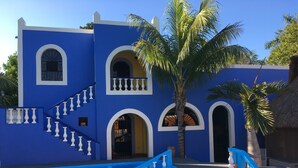 A blue building with a pool, stairs, and palm trees. - Hacienda San Pedro Nohpat (Kanasín)