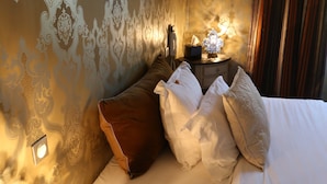 Ein Hotelzimmer mit Bett, Kissen, einem Nachttisch und einer Wand mit Musterdesign.