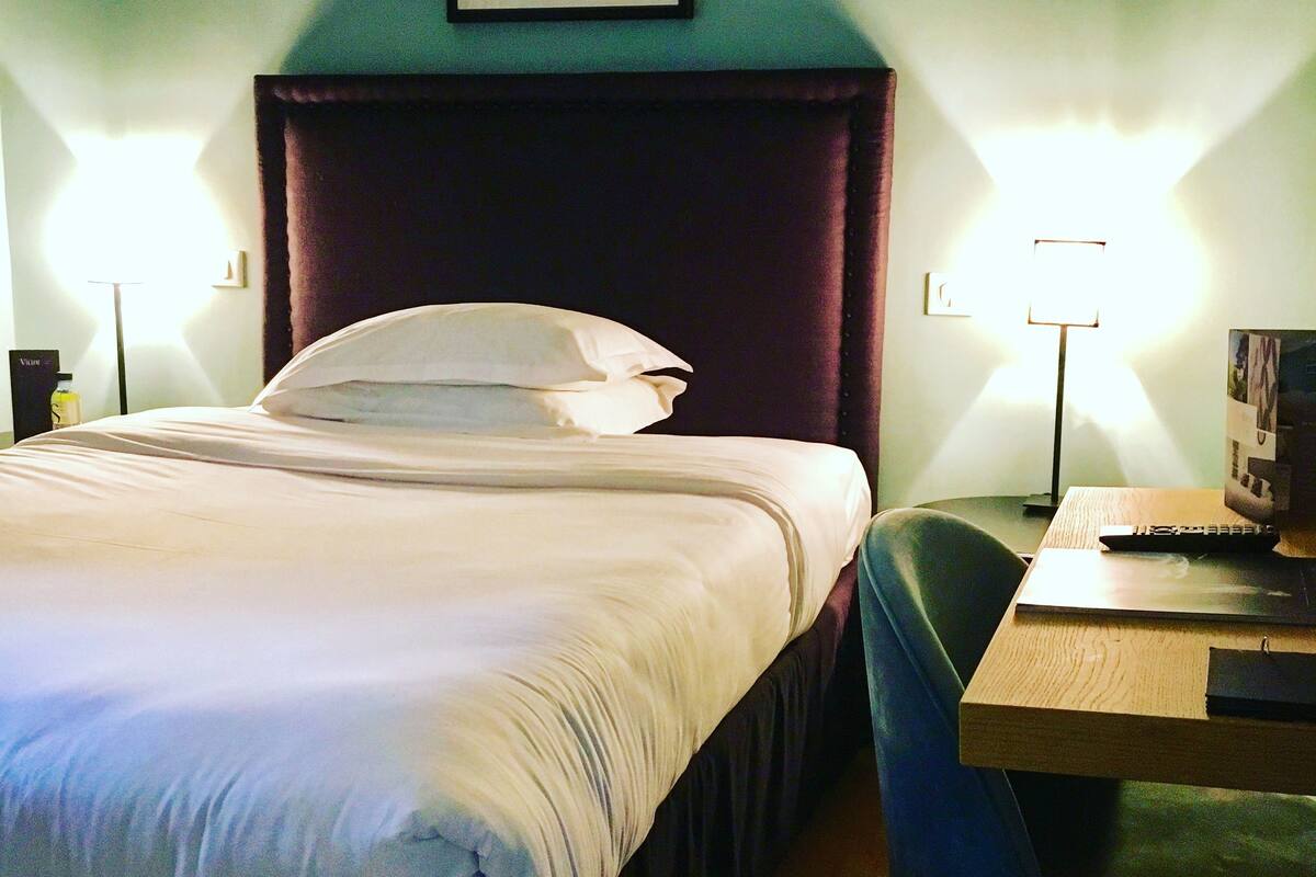 A hotel room with a bed, a desk, and a chair.