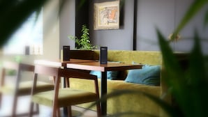 Ein Zimmer mit einem gelben Sofa, einem Holztisch und einem gerahmten Kunstwerk an der Wand.