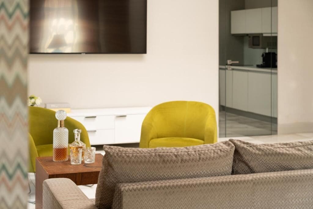 Un salon moderne avec un canapé, une table basse en bois et un téléviseur fixé au mur.