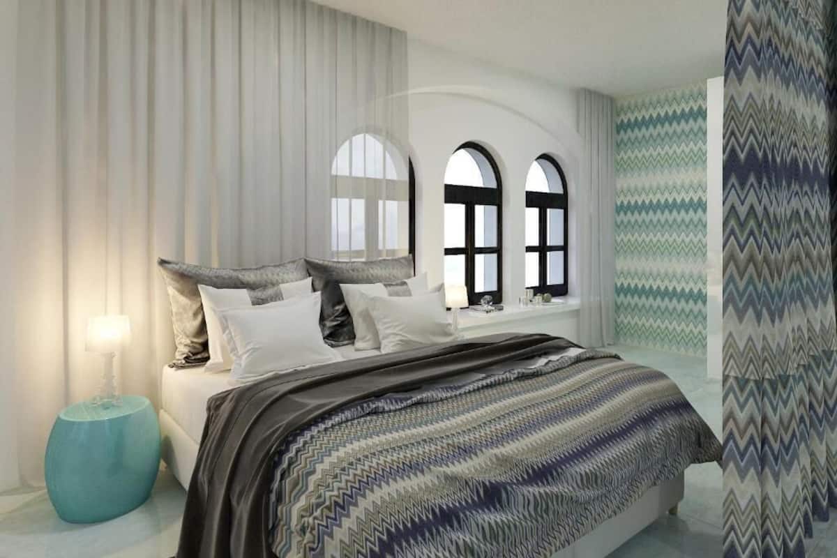 Une chambre à coucher avec un lit, des rideaux, une table de chevet et une fenêtre donnant sur un beau paysage.