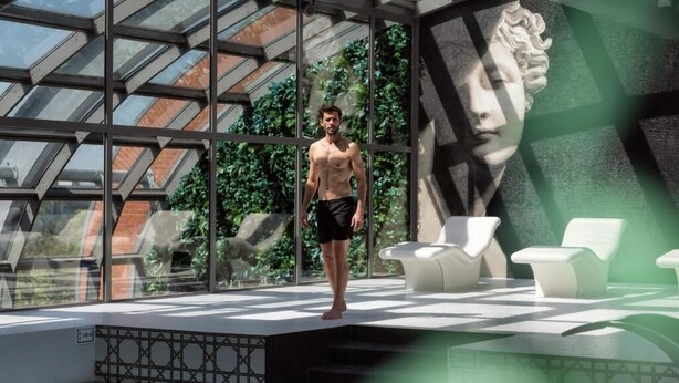 Un espace piscine intérieur moderne doté d’un plafond en verre, d’une statue et de chaises longues.