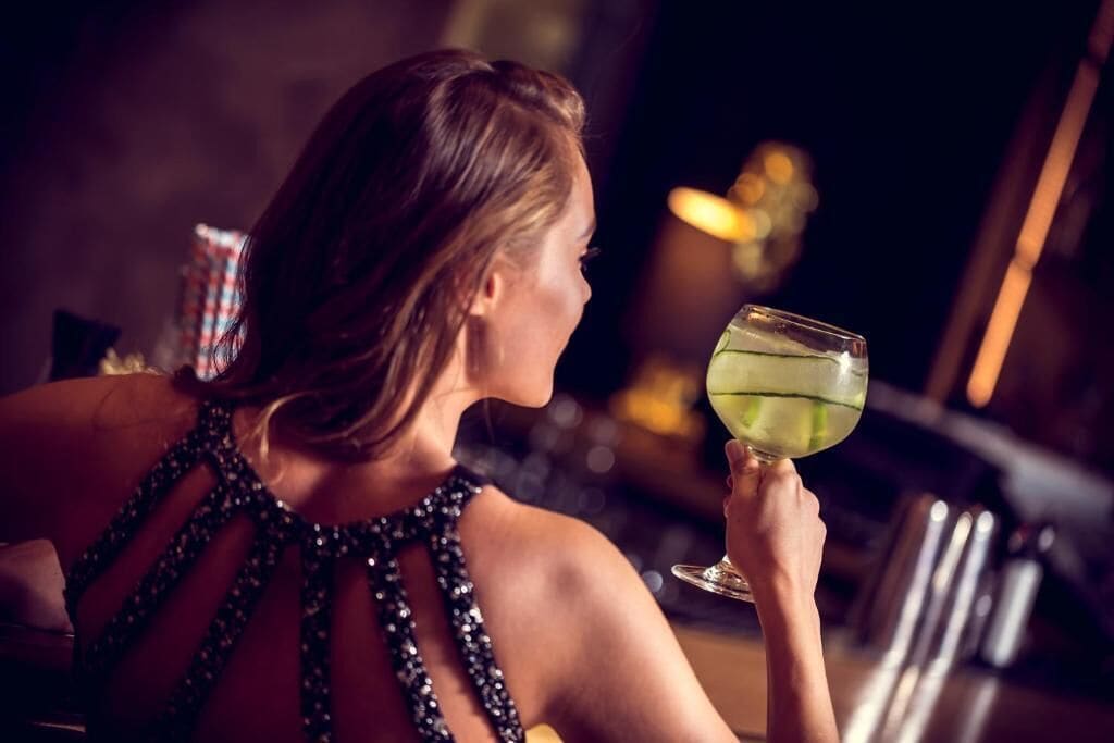 A person holding a cocktail glass at a bar.