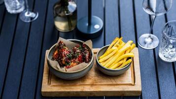 A wooden table with a bowl of fried chicken and a bowl of French fries.