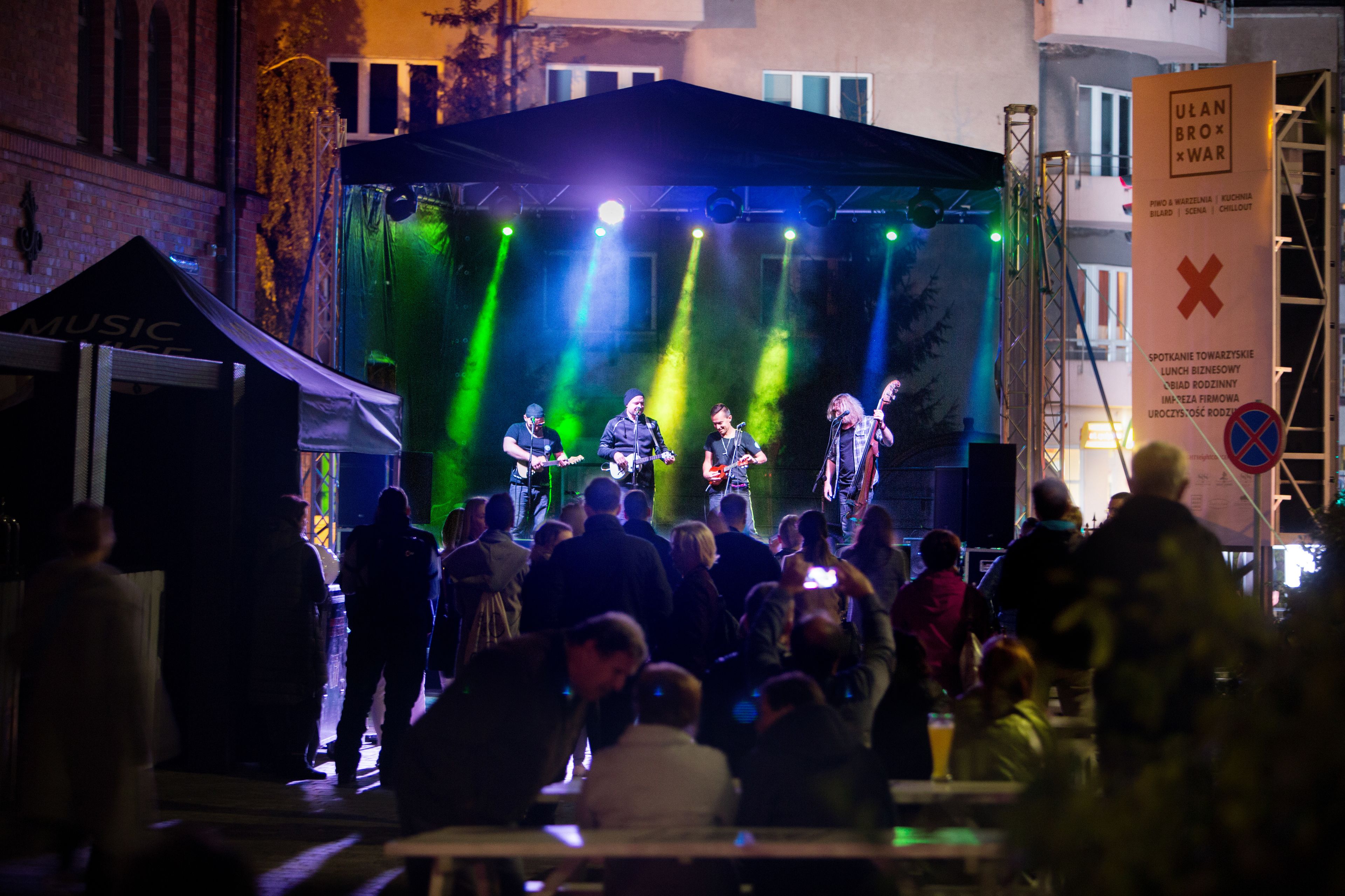 Un groupe de musique se produit sur une scène en plein air devant une foule de spectateurs.