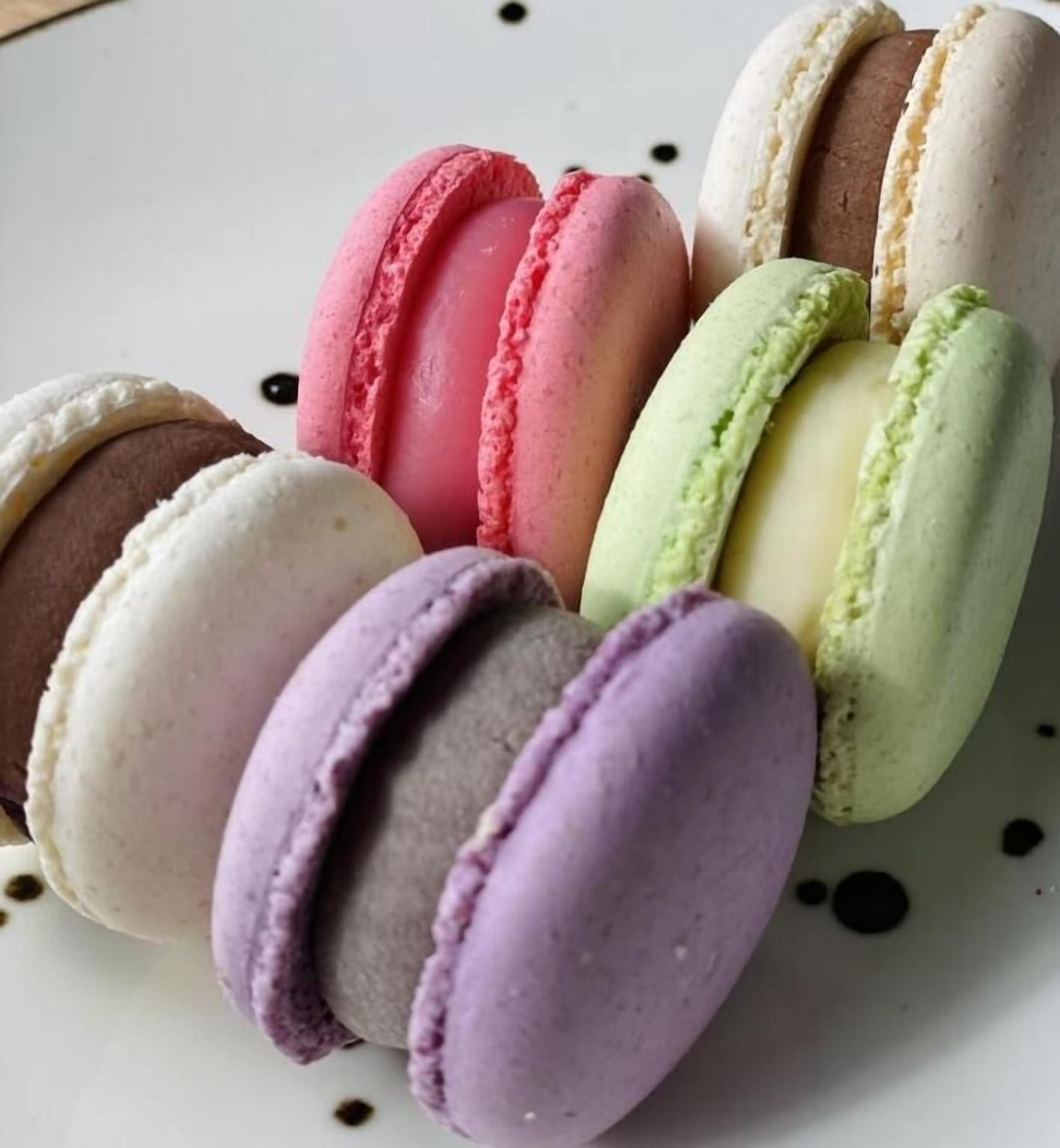 Diverse macarons in verschillende kleuren, gerangschikt op een bord.
