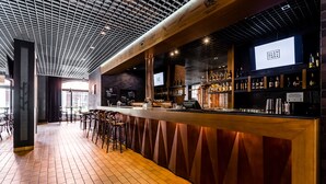 Un espace bar doté d’un long comptoir, de tabourets et d’une variété de bouteilles et de verres.
