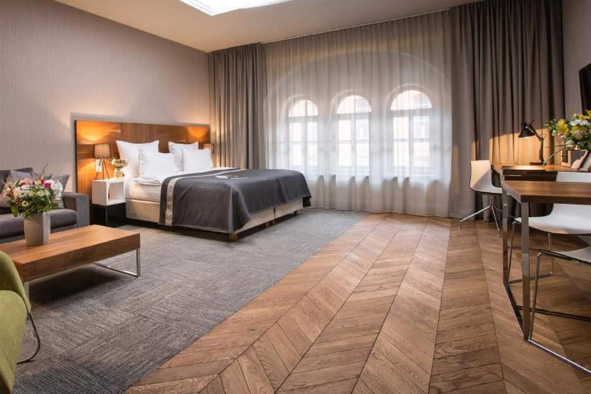 Une chambre d’hôtel avec un lit, un canapé, un bureau et une chaise.