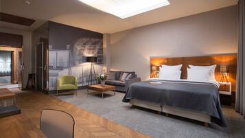 Ein modernes Hotelzimmer mit einem großen Bett, einer Couch, einem Schreibtisch und einem Sessel.