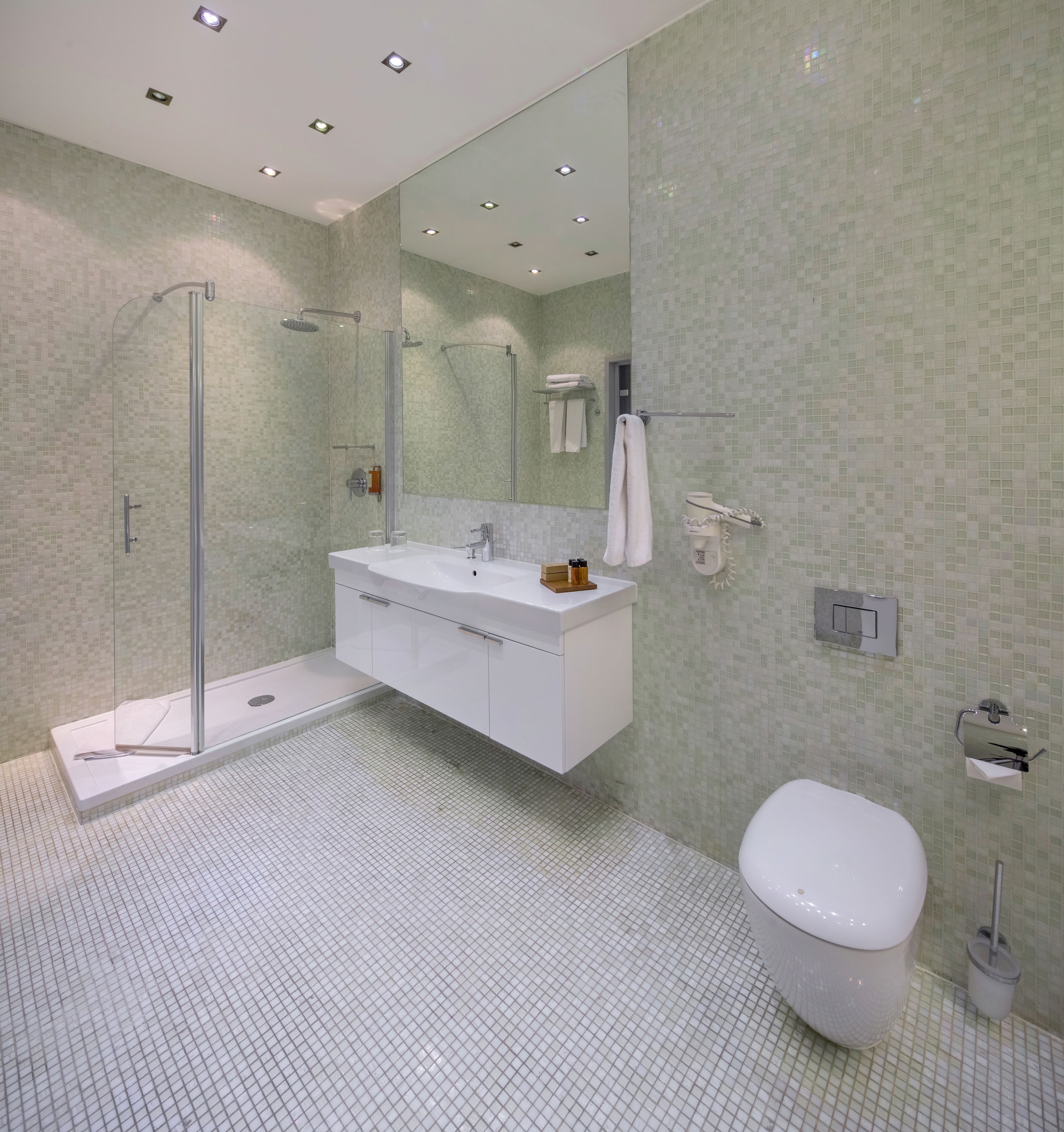 A modern bathroom with a glass-enclosed shower, a white vanity, and a toilet.