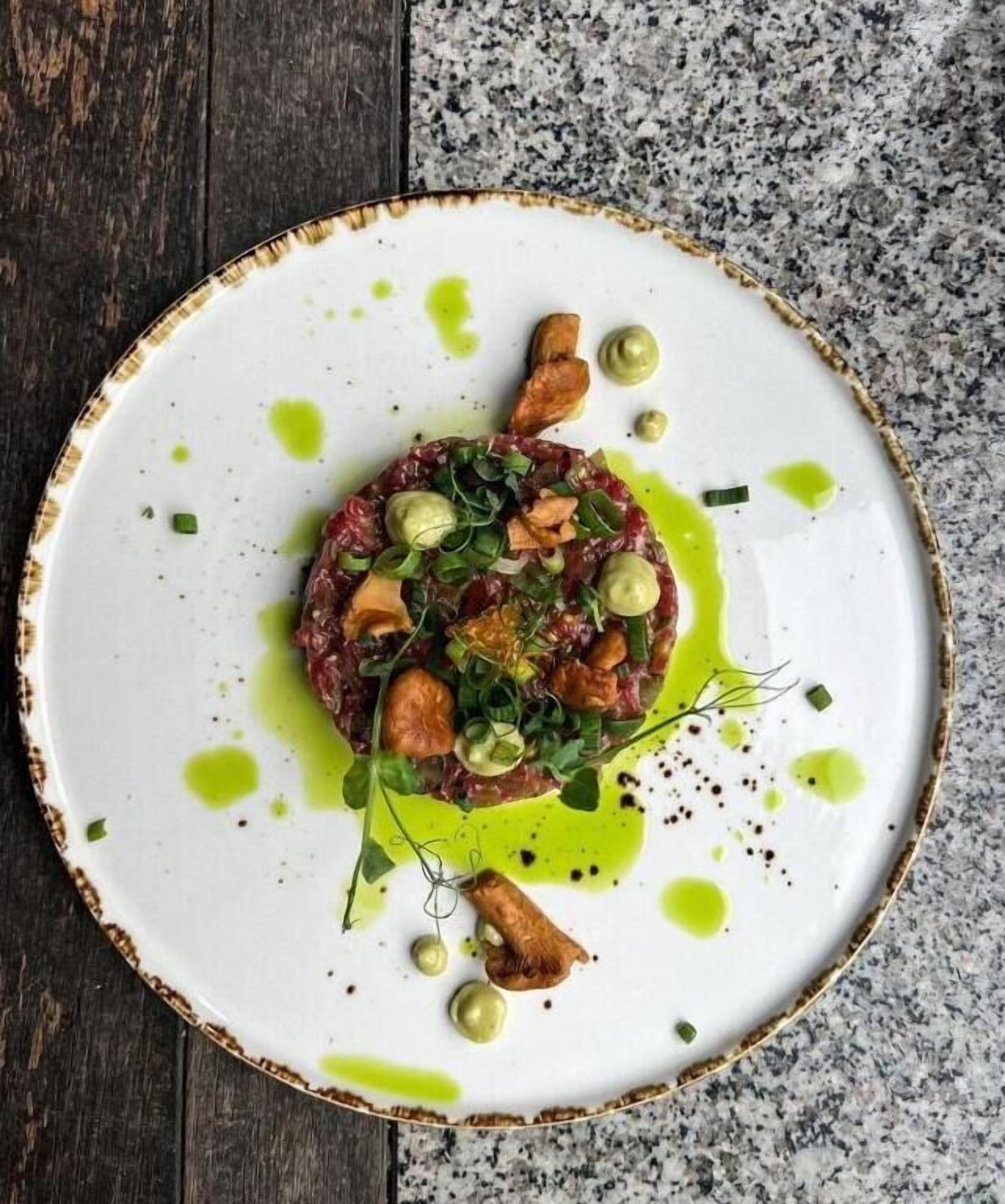A plate of food with a white rim and green sauce.