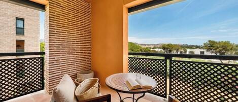 A balcony with a view of a cityscape, a brick wall, and a round table with a book.