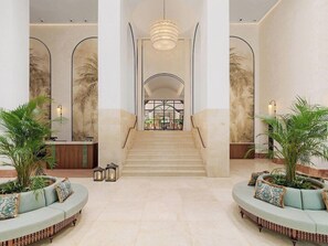 A hotel lobby with a central staircase, two seating areas with plants, and a reception desk. - Vincci Estrella de Mar  (Marbella)