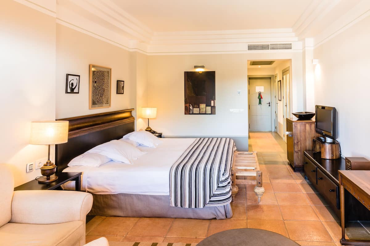 Ein Hotelzimmer mit Bett, Nachttischlampen, Fernseher und Schreibtisch.