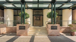A hotel entrance with a glass canopy, brick steps, and potted plants. - Vincci Estrella de Mar  (Marbella)