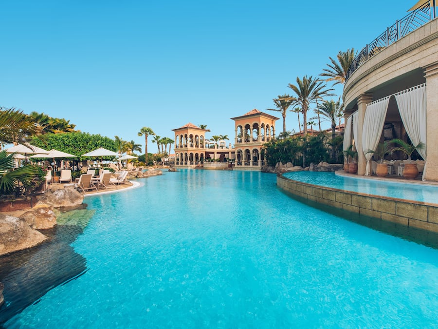 Een buitenzwembad, parasols bij het zwembad en ligstoelen