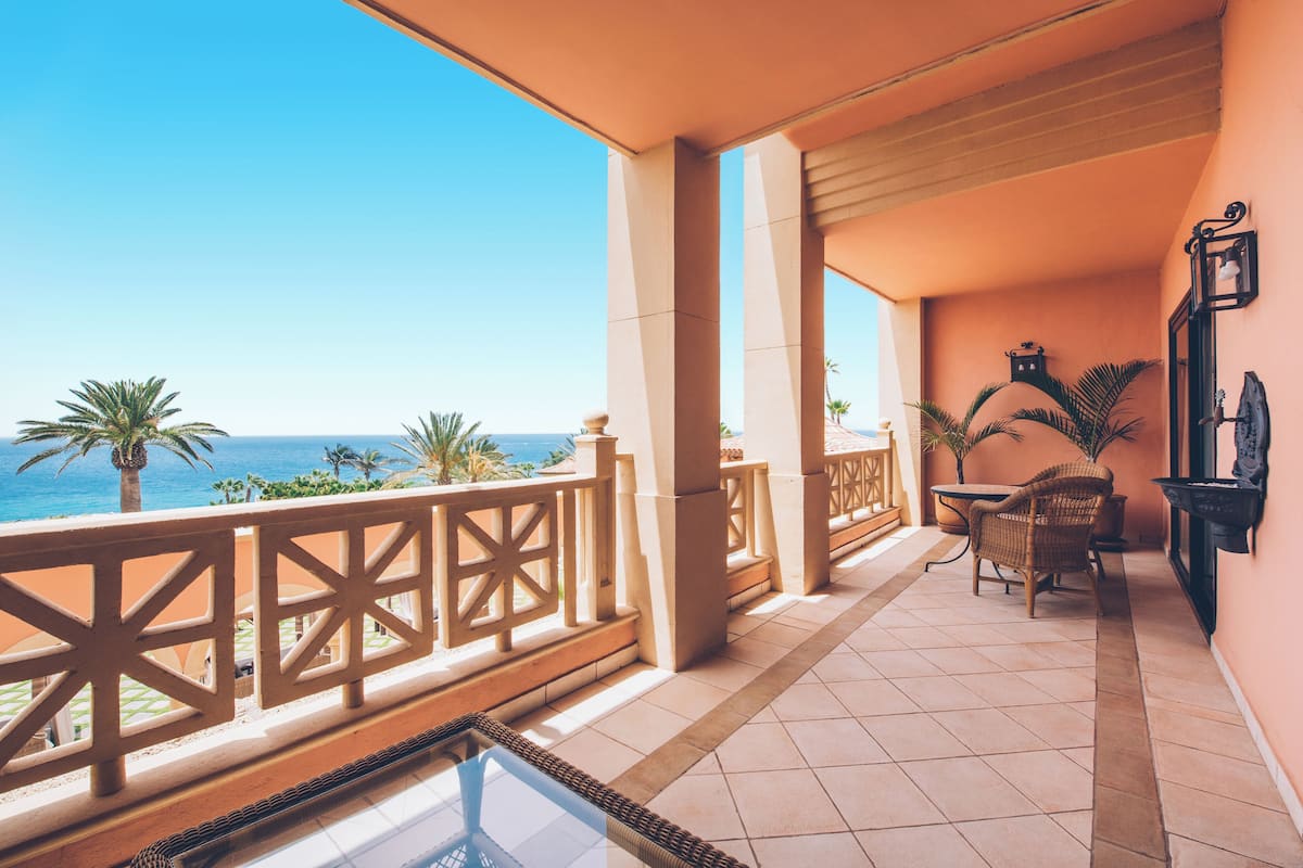Un balcon avec vue sur l’océan, comprenant une table, des chaises et une balustrade.