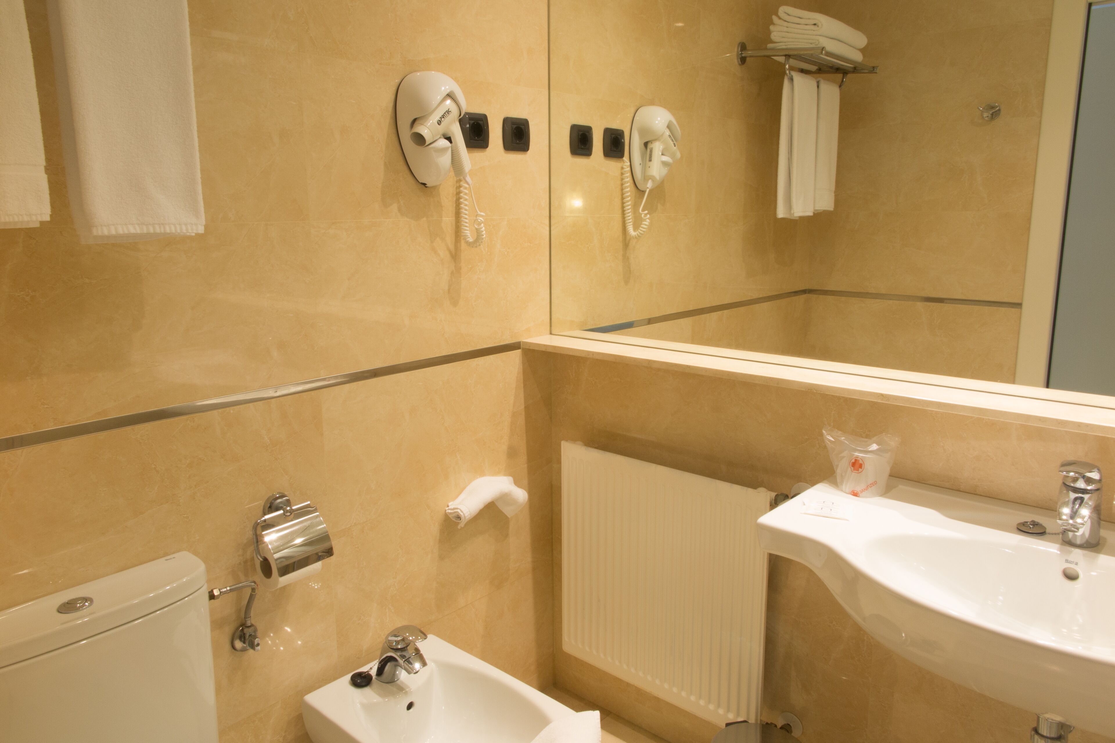 Un baño con inodoro, lavamanos y dos teléfonos fijos en la pared.