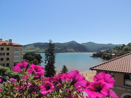 Vista costera con playa, montañas y edificios.