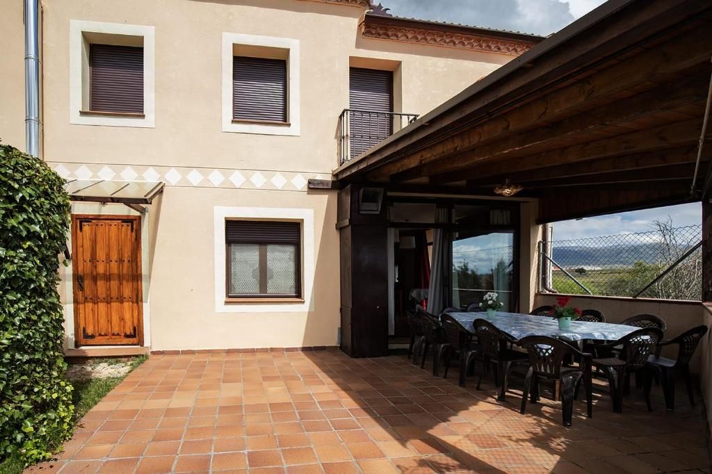 A building with a tiled patio, a wooden door, and a table with chairs.