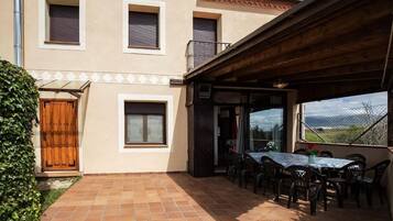 A building with a tiled patio, a wooden door, and a table with chairs.